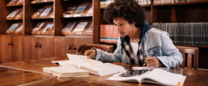 A photo of a young man studying books in a library