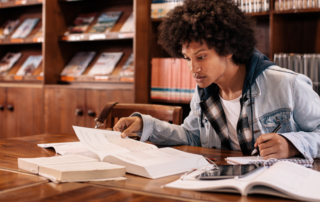 A photo of a young man studying books in a library