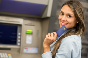 An image of a young woman about to put a card in an ATM machine.