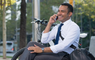 An image of a young businessman sitting on a parkbench and talking on his cellphone.