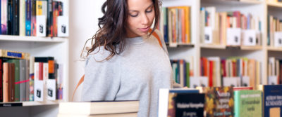 A photo of a young woman looked at books on display in a store or library