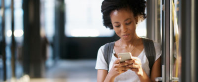 A photo of a young woman looking at her cellphone.